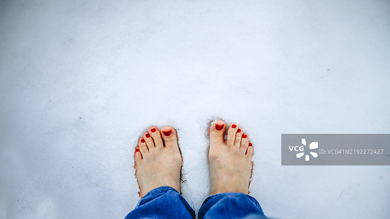 雪天里涂有红色指甲油的脚，体现冬季正念和扎根仪式。横幅，留白和俯视图图片素材