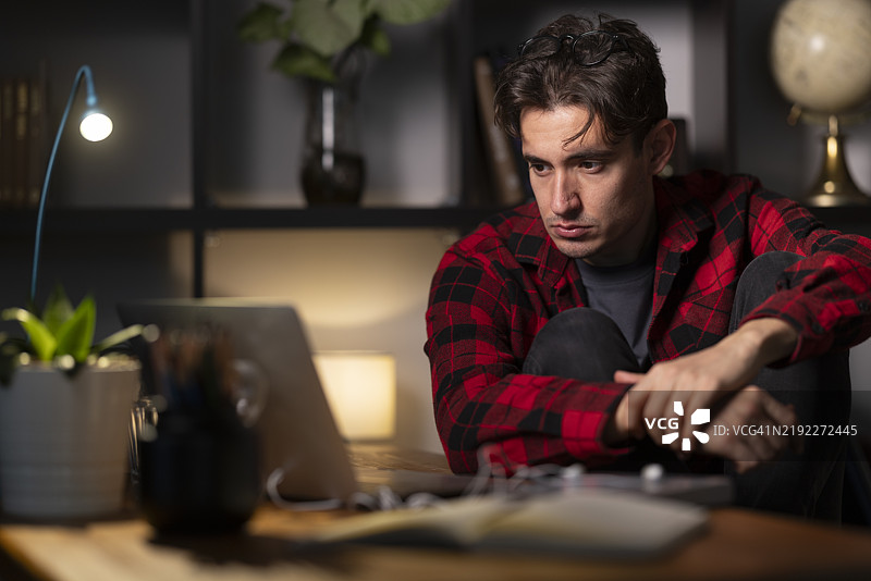 专注的年轻人在家办公室里加班使用笔记本电脑图片素材