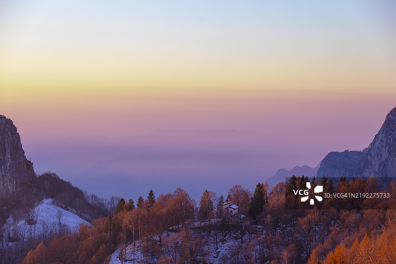 宁静山脉上方的梦幻粉橙色天空与森林图片素材