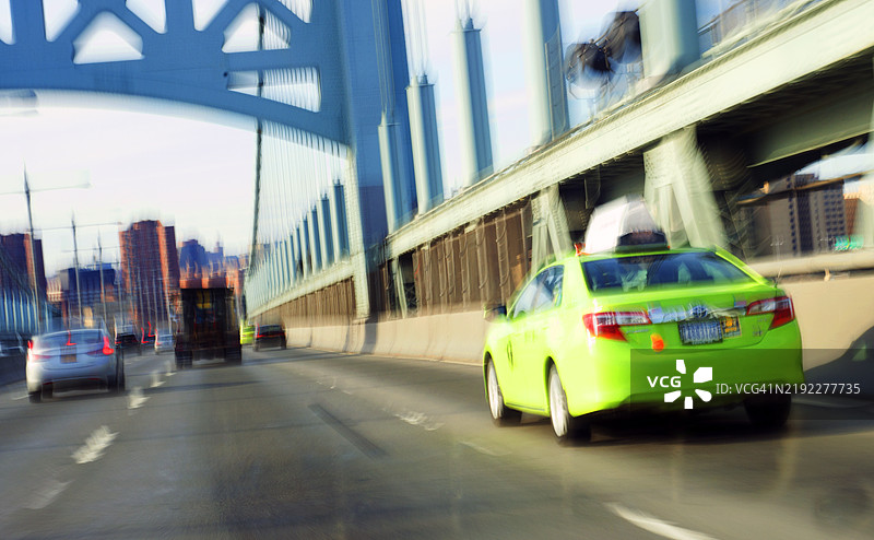 一张运动模糊的照片，展示了一辆街头出租车（也称为绿色出租车）在前往纽约曼哈顿的途中穿过RFK大桥。图片素材