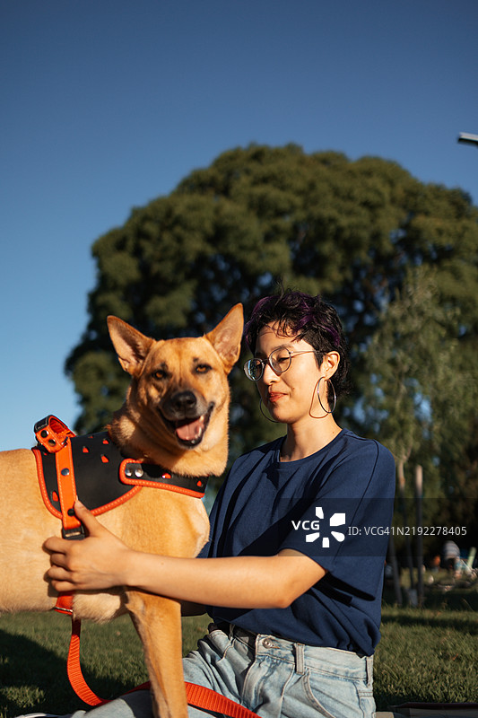 微笑的亚洲女性在公园里与她的狗在户外玩耍图片素材