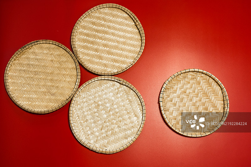 黄色编织竹盘置于幸运的红色背景上图片素材