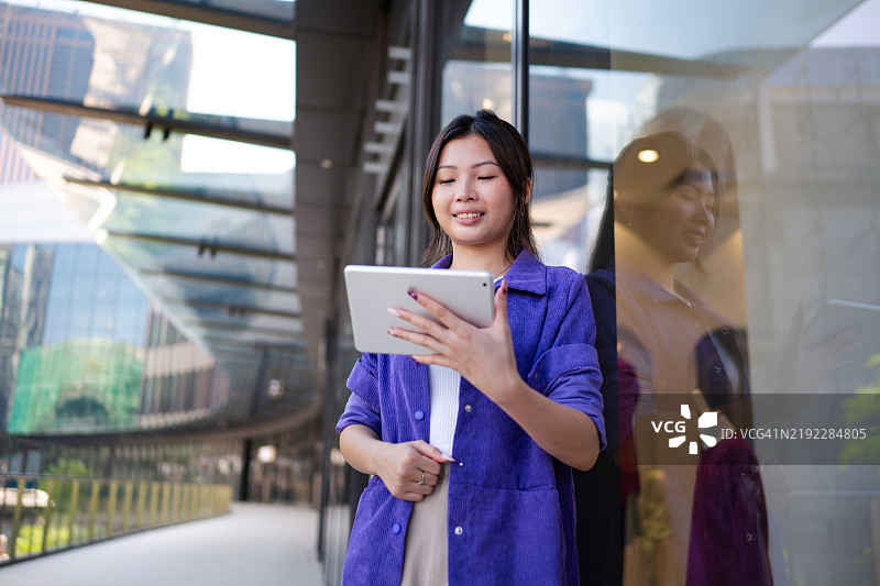 年轻的亚洲女性企业家手持数字平板电脑图片素材