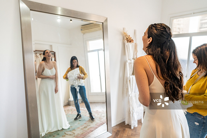 新娘在婚纱店试穿婚纱，销售员在旁协助。图片素材