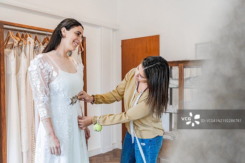 女裁缝在婚纱店为新娘调整婚纱图片素材