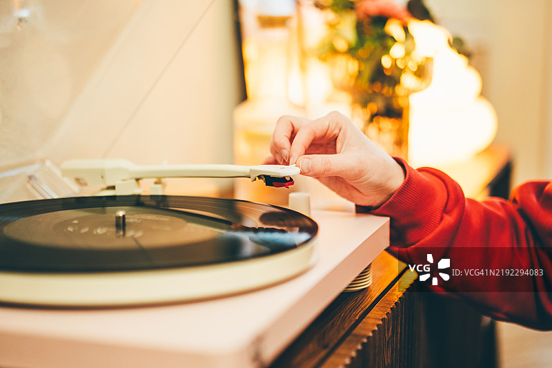 一位女性在家中用黑胶唱片播放器聆听音乐的特写镜头。图片素材