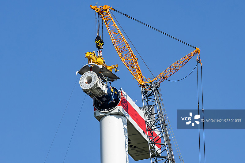风力发电机建设现场 - 大型起重机将涡轮机吊入涡轮机箱中图片素材
