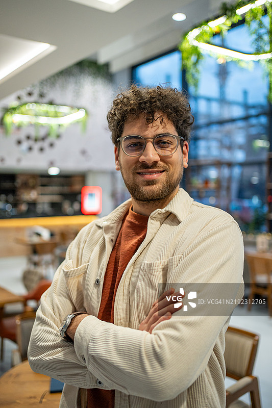 现代年轻男子正面肖像，双臂交叉，注视着镜头。图片素材