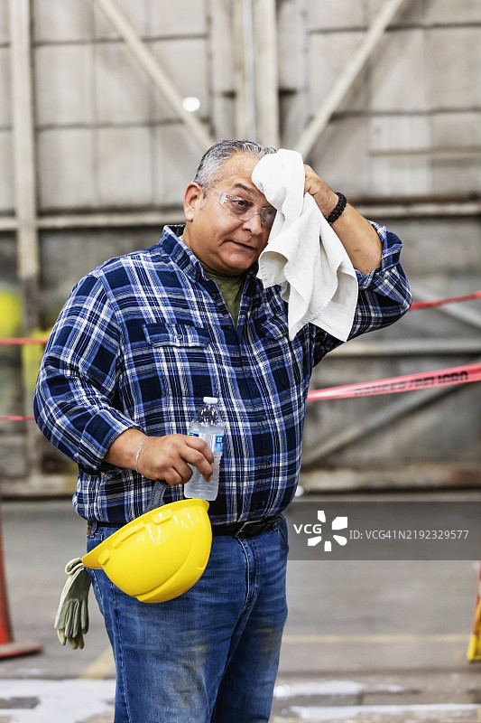 成熟的西班牙裔男性在工厂工作，正在休息图片素材