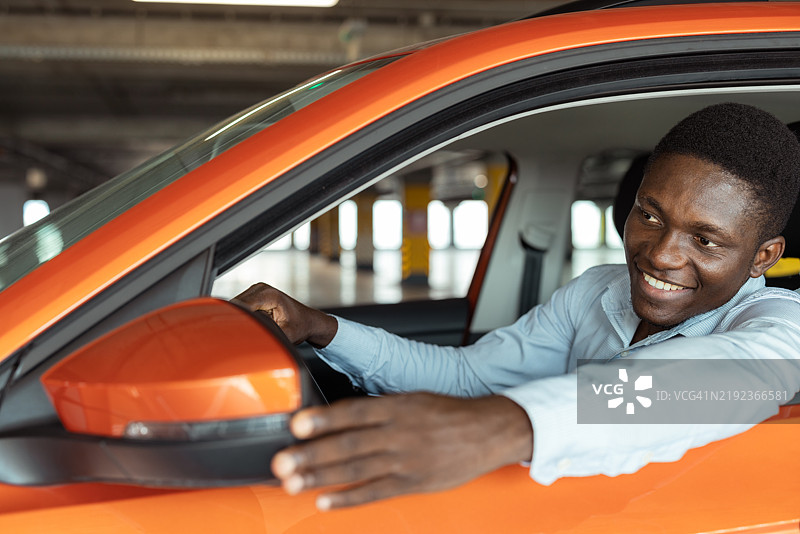 快乐的黑人男性司机在开车前调整侧视镜图片素材