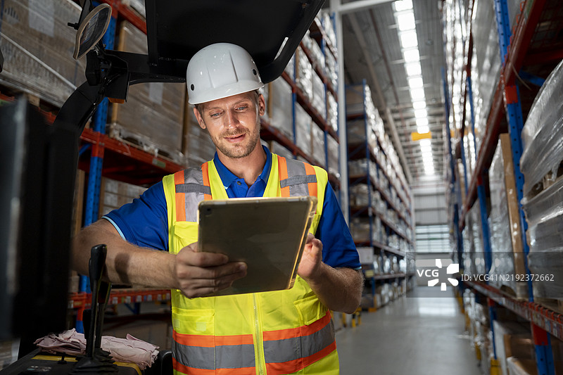 仓库员工在叉车上使用数字平板电脑图片素材