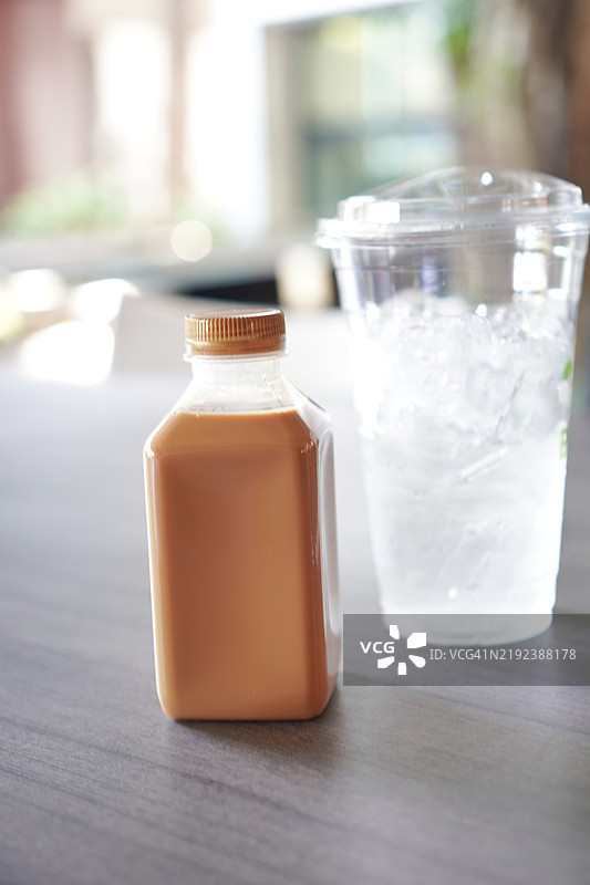 泰国茶装在塑料瓶中，冰块放在塑料杯里图片素材