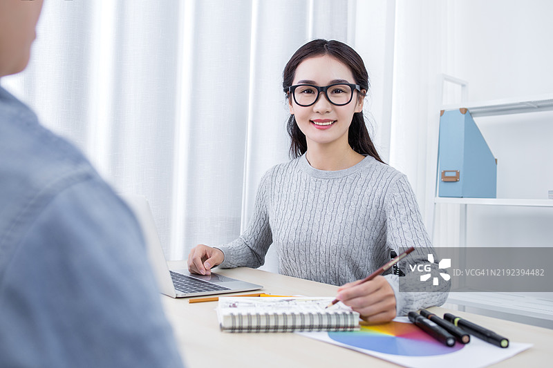 吸引人的女性设计师与同事在办公室工作图片素材