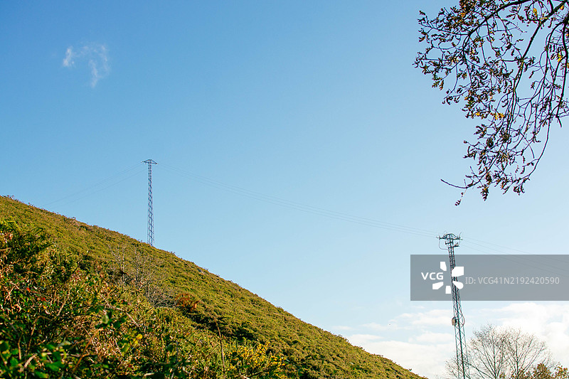 电信塔矗立在蓝天之下的绿色山丘上图片素材