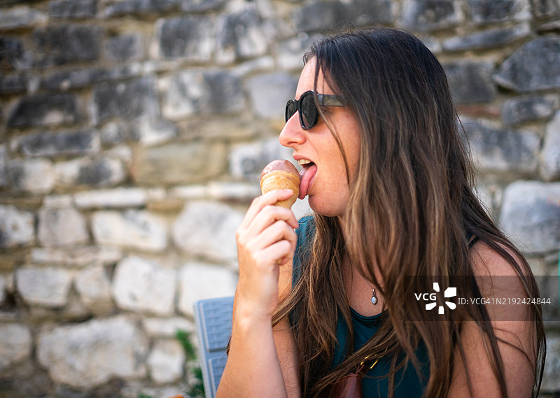 年轻女性在石墙前享受冰淇淋蛋筒图片素材