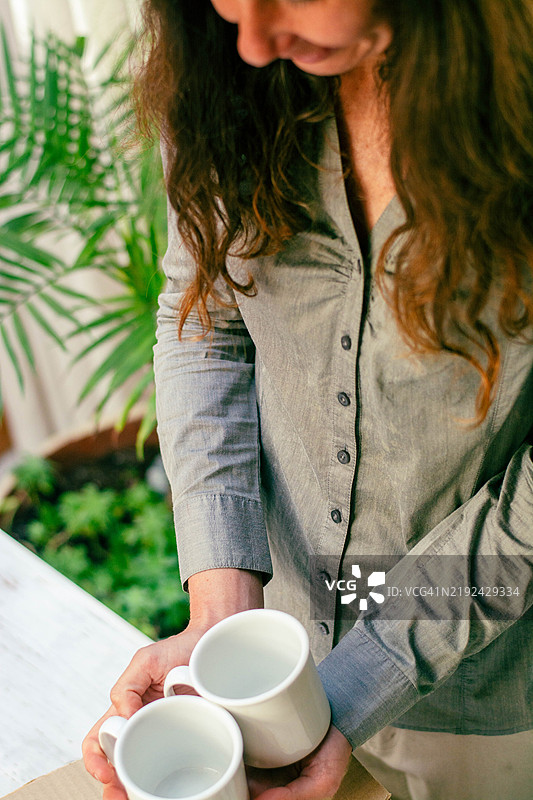 女人在家居环境中手持两个空白色杯子图片素材
