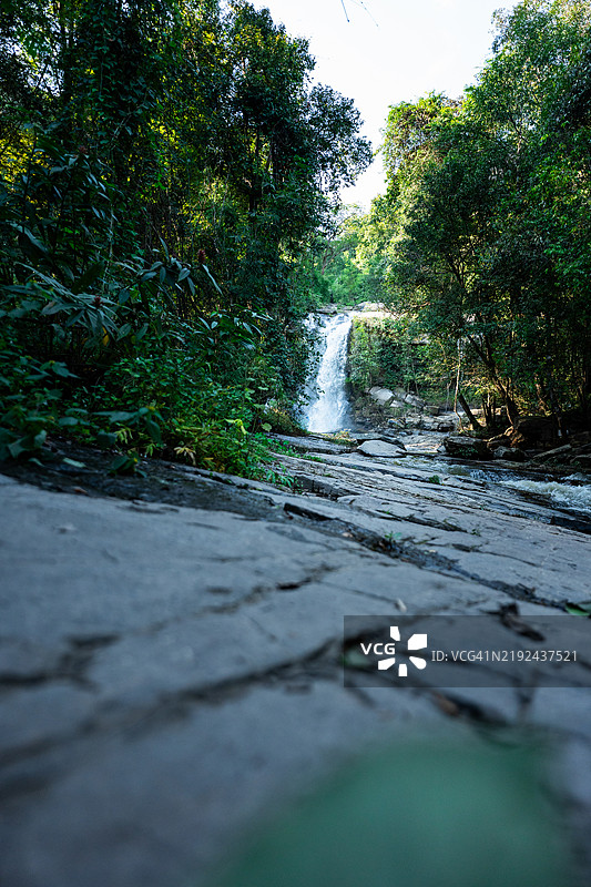 瀑布从岩石地形倾泻而下，周围是郁郁葱葱的森林图片素材