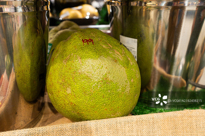 市场展示中放置在麻布袋上的大型绿色柚子图片素材