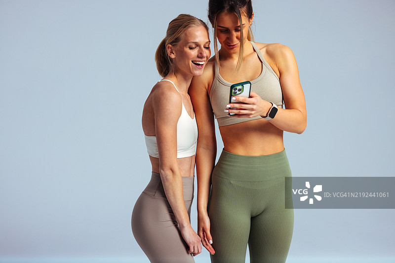 两位健康的女性在查看智能手机时分享欢笑图片素材
