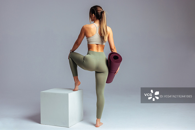 运动女性在健身训练后手持瑜伽垫图片素材
