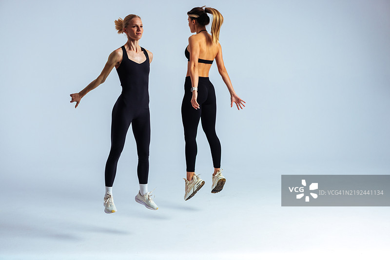 两位健康的女性在工作室中同步跳跃图片素材