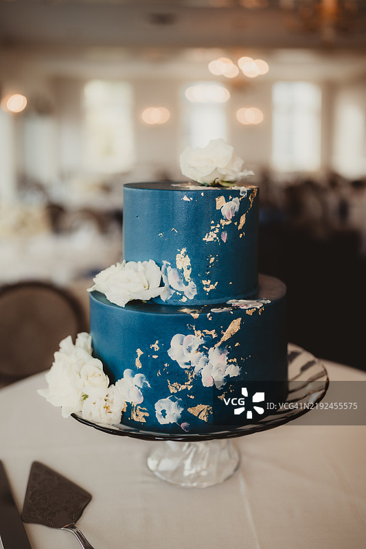 蓝色分层婚礼蛋糕，装饰有金箔和花朵图片素材