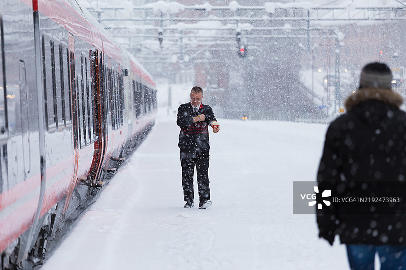 在暴风雪中，列车长和乘客在利勒哈默尔火车站的站台上。图片素材