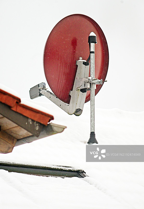 雪覆盖的屋顶上的圆形电视天线图片素材
