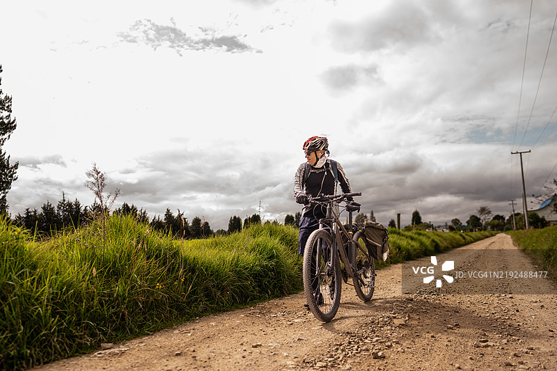 老年男子在泥土路上骑自行车图片素材