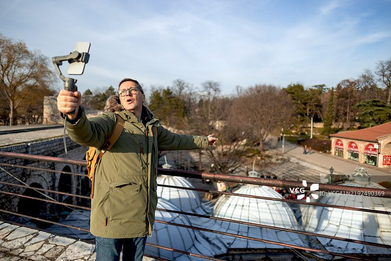 成熟男性在街头行走并记录他的旅行经历图片素材
