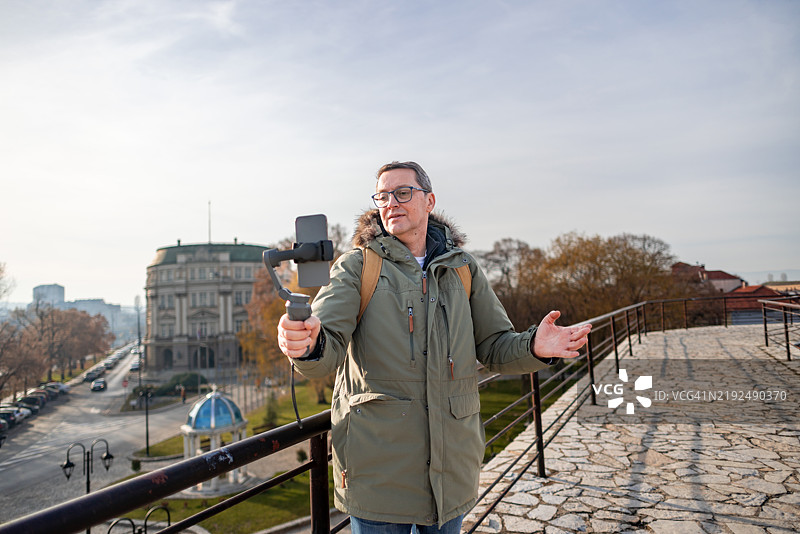 成熟男性在街头行走并记录他的旅行经历图片素材