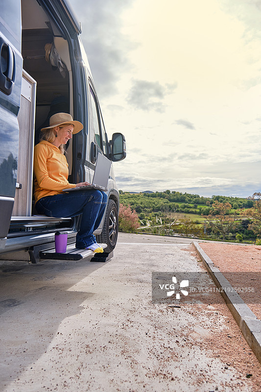 在停放的房车内使用笔记本电脑的女性图片素材