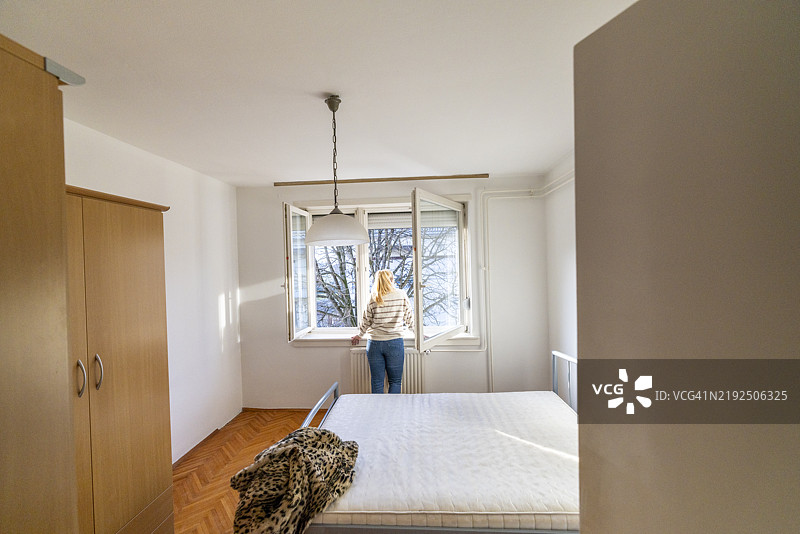 在明亮窗户旁沉思的中年白人女性图片素材