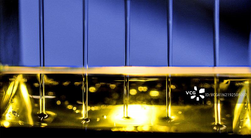 紫色光纤管在金色水面和管道上方。图片素材