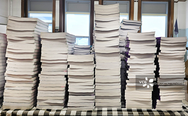 展示在桌子上的白色封面书籍，带有格子图案。图片素材