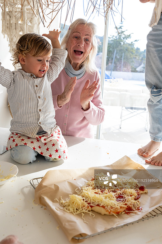 快乐的多代家庭在厨房一起制作披萨图片素材