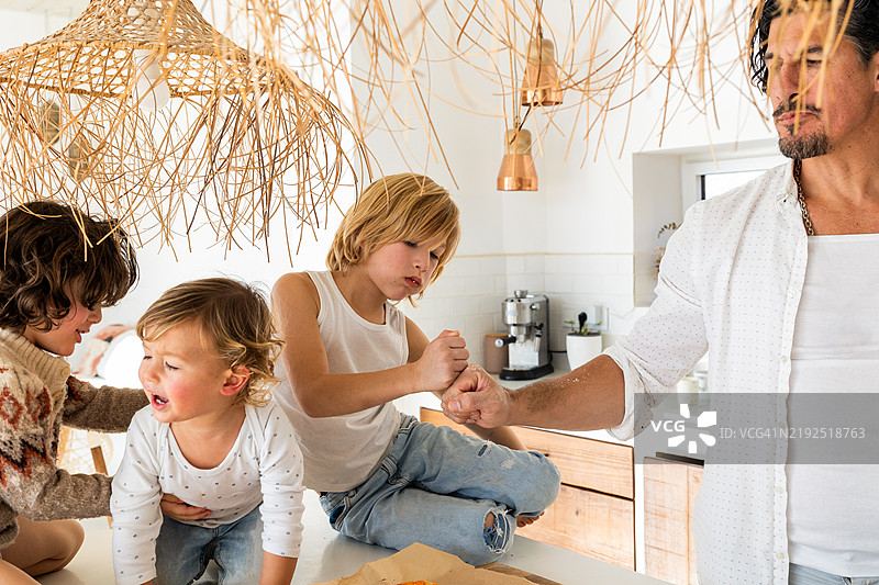 快乐的家庭在厨房里一起吃披萨图片素材