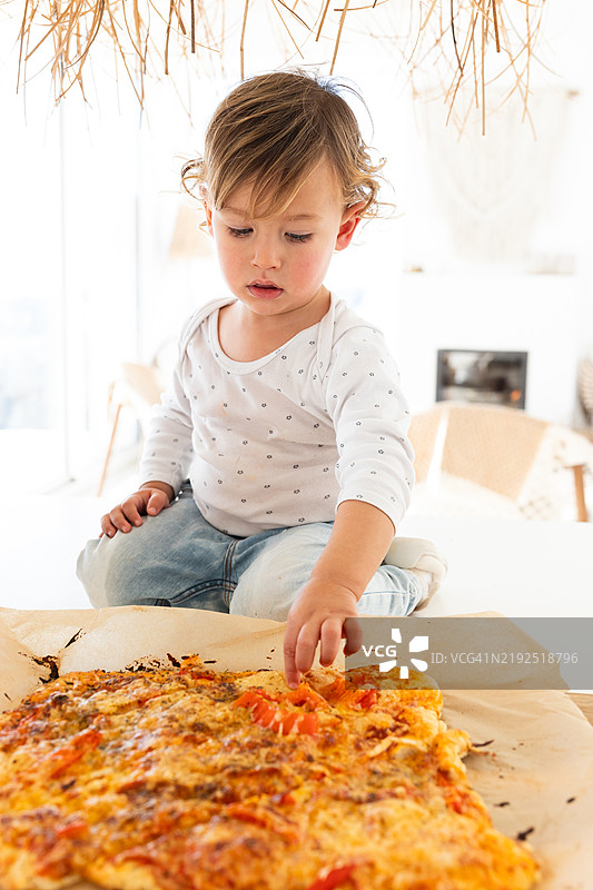 小男孩在家里伸手去拿刚做好的披萨图片素材