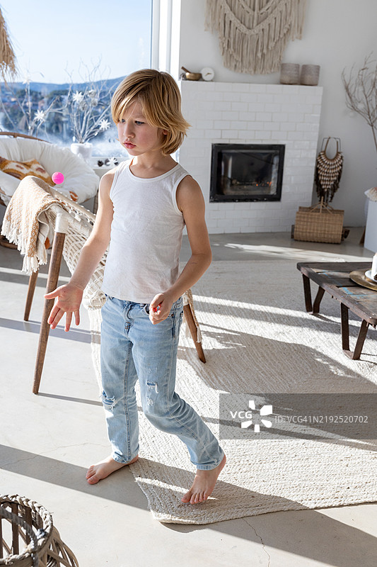 金发男孩在客厅里玩粉色球杂耍图片素材