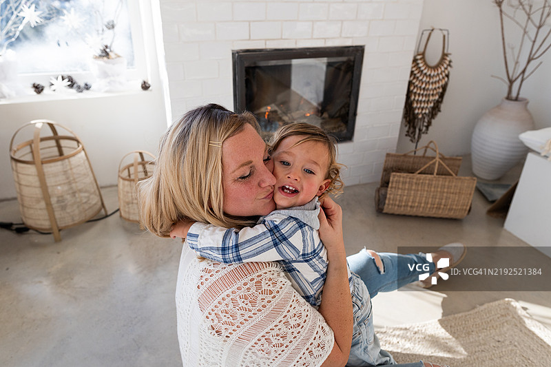 母亲在客厅里拥抱并亲吻她的儿子图片素材