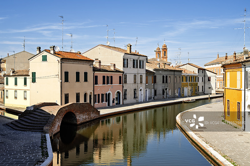 科马基奥的一条运河，两侧有桥和房屋。这些房屋的颜色和风格各不相同。图片素材