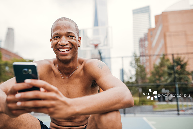 篮球运动员在球场上微笑着拿着手机图片素材