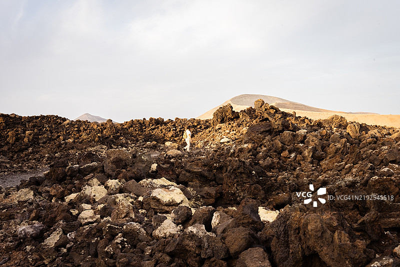 地质学家在加那利群岛的火山景观中研究，走在凝固的熔岩石和独特的地质构造之间，检查岩石地形。图片素材