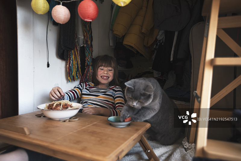 有趣的快乐小孩与他的猫一起吃意大利面的人像图片素材