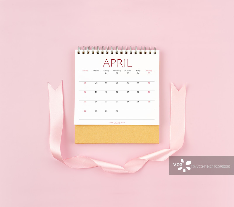 2025年4月的桌面日历，配有粉色丝带，位于图像中心。图片素材