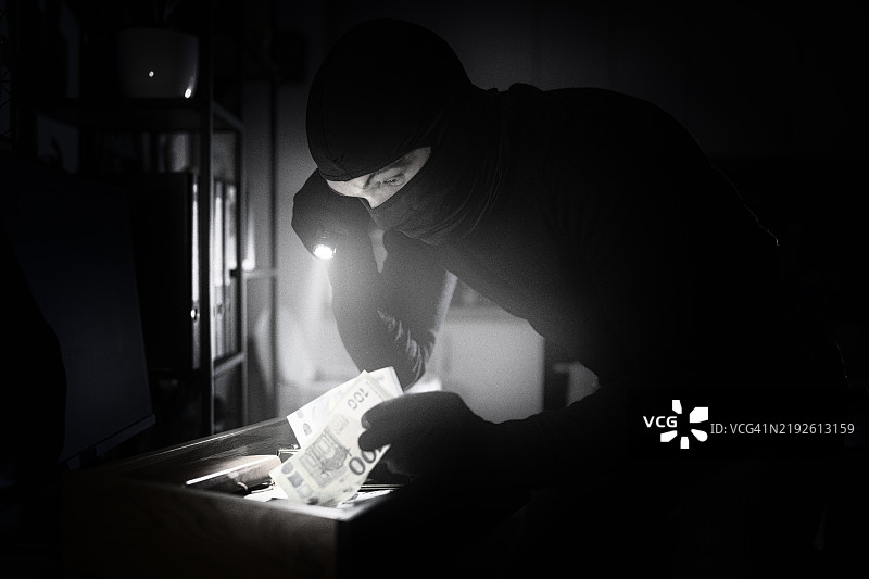 戴面具的小偷闯入房屋。图片素材