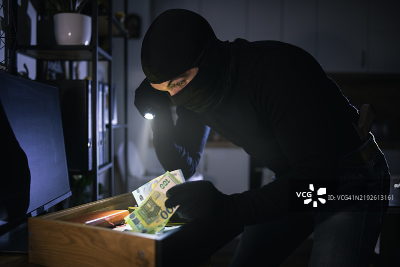 戴面具的小偷闯入房屋。图片素材