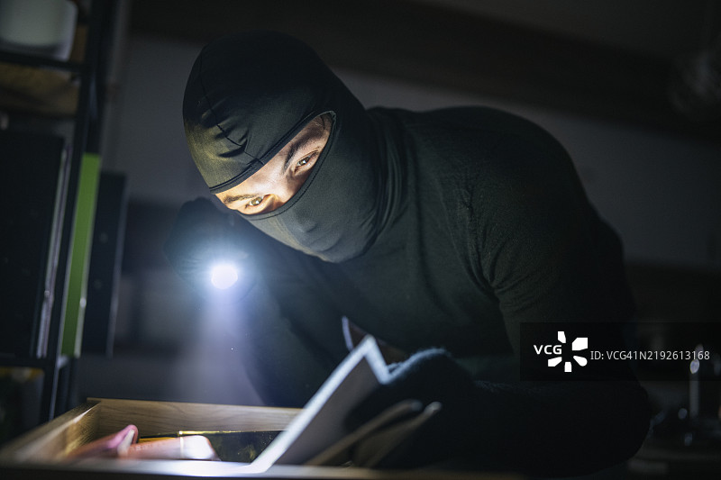 戴面具的小偷闯入房屋。图片素材