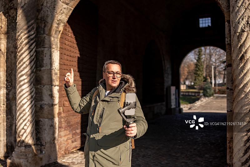 成熟男性在街头行走并记录他的旅行经历图片素材