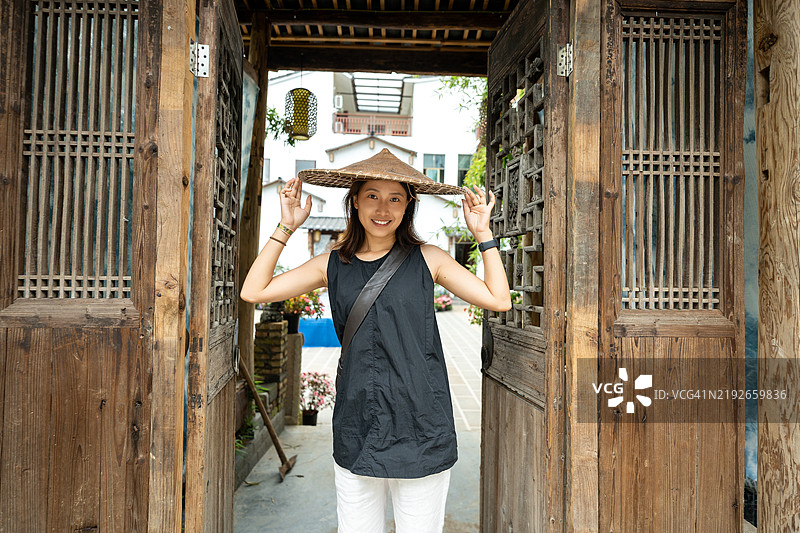 一位年轻的中国女性正在云南旅行，戴着当地的草帽。图片素材